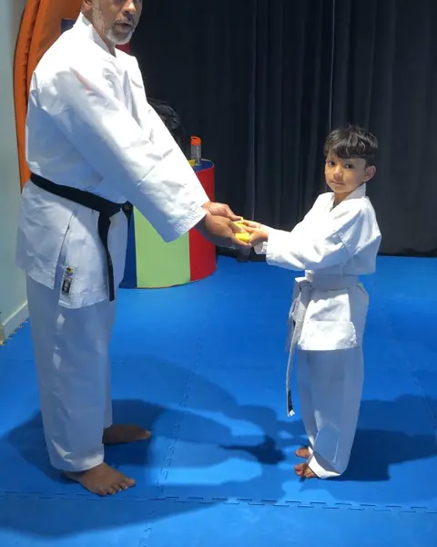 Instructor shaking hands with a young student after his grading