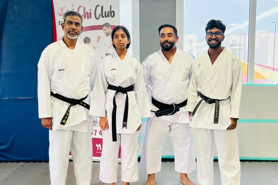 Chi Club black-belt instructors in front of the club banner