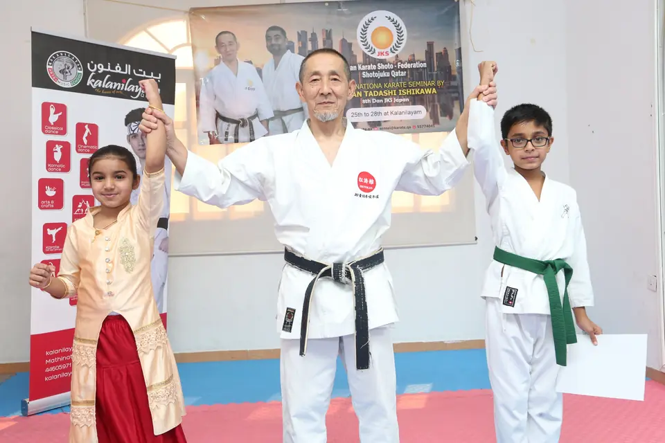 Sensei raising the hands of two young students after their grading